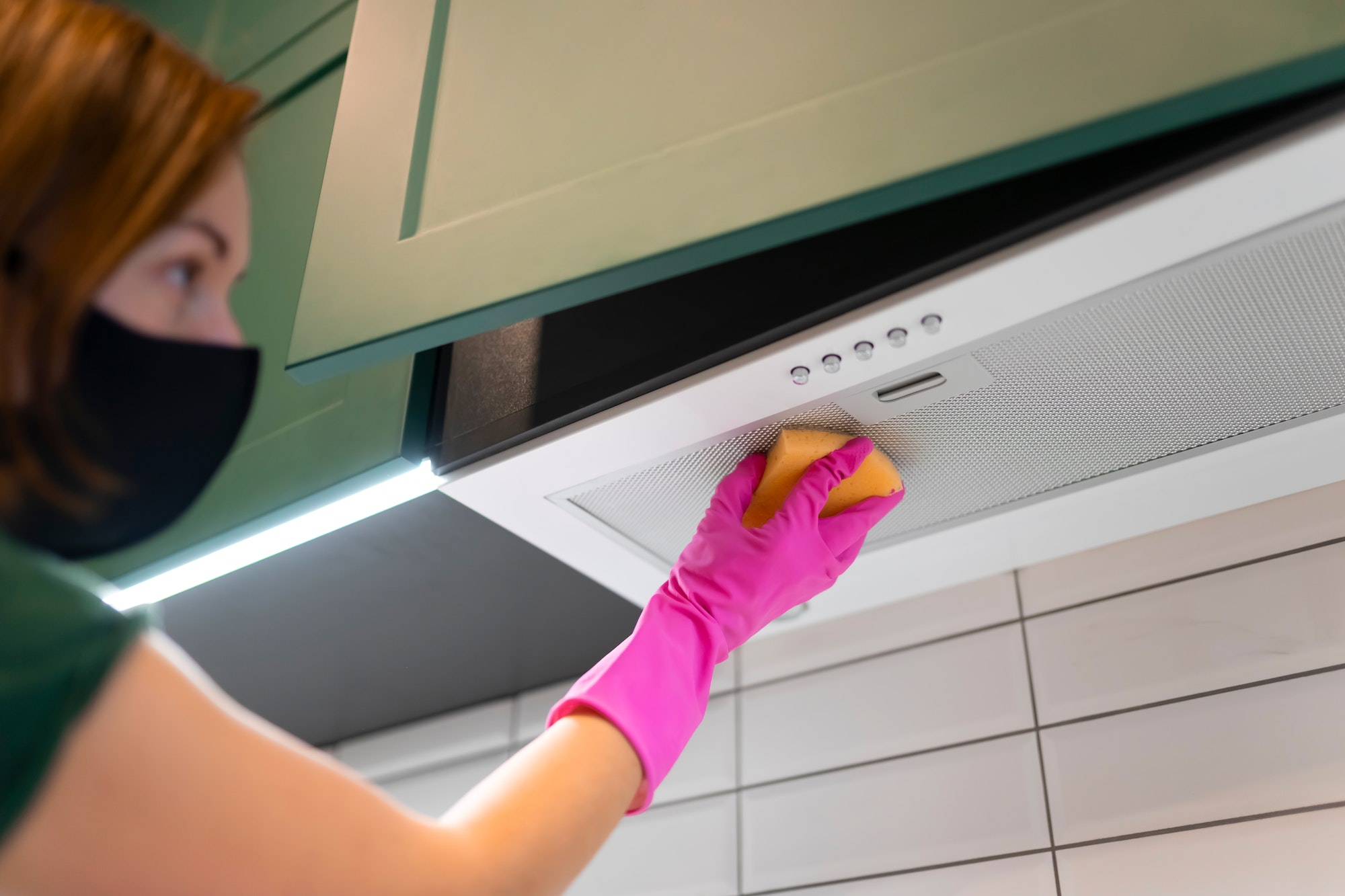 Woman cleaning the hood in the kitchen